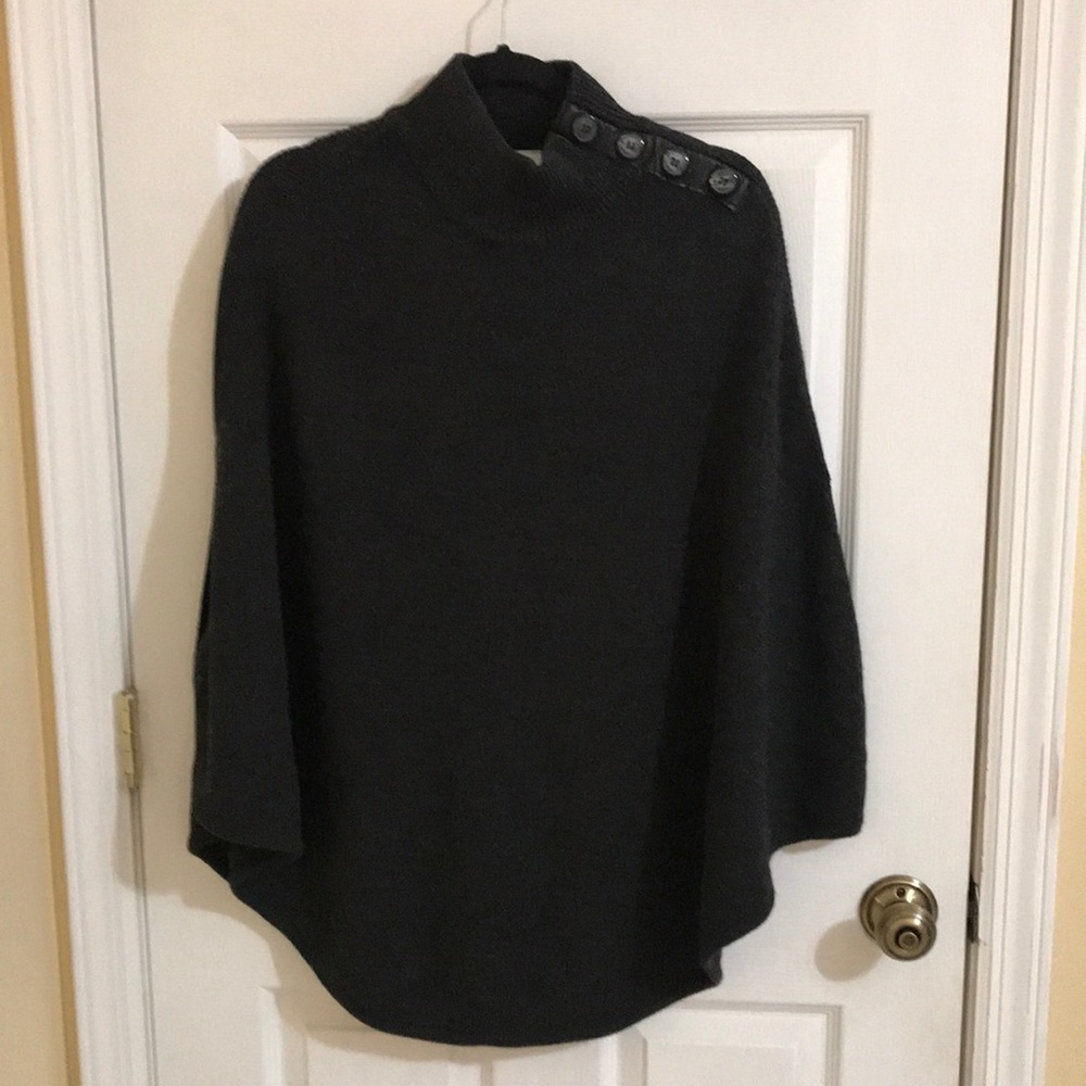 Grey knit poncho imitation black leather trim and four black shoulder buttons.